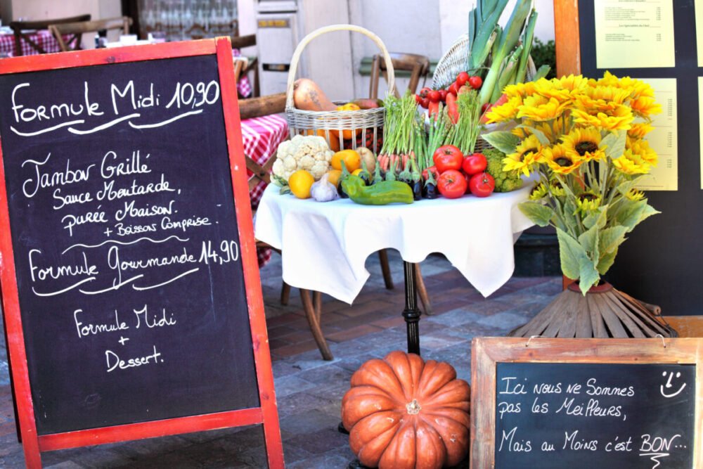Menu board with arrangement of vegetables and sunflower at French restaurant
